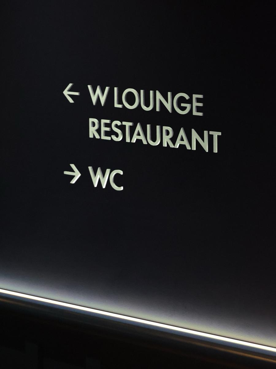 W Hotels wordmark signage on dark wood panel